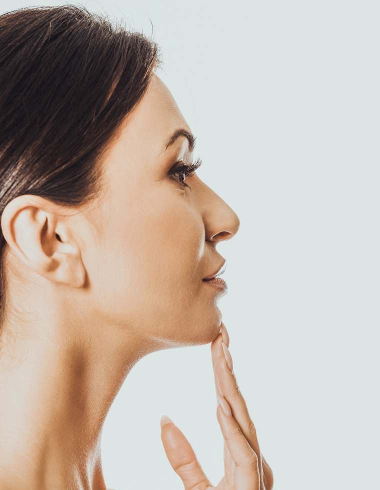 Perfil feminino com a mão no queixo (rinoplastia)